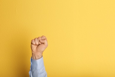 Young man showing clenched fist on color background. Space for text