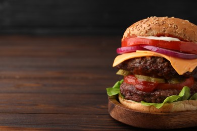 Photo of Tasty cheeseburger with patties on wooden table, closeup. Space for text