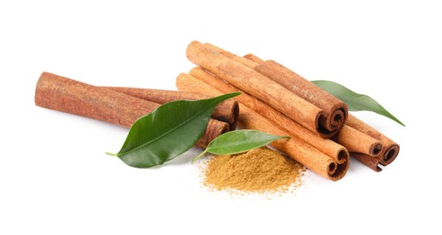 Photo of Dry aromatic cinnamon sticks, powder and green leaves isolated on white