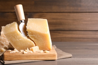 Parmesan cheese with wooden board and knife on table. Space for text