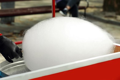 Man making cotton candy with machine outdoors, closeup