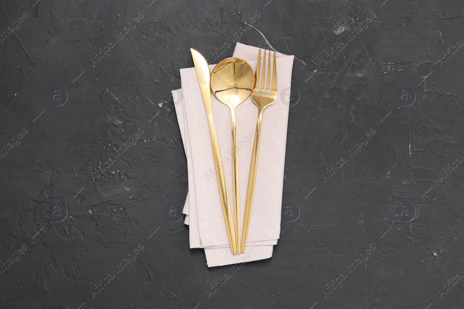 Photo of Beautiful cutlery set and kitchen towel on black table, top view