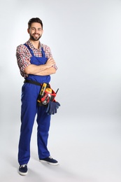 Photo of Full length portrait of construction worker with tool belt on light background. Space for text