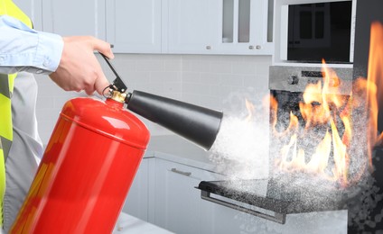 Man putting out burning oven with fire extinguisher in kitchen, closeup