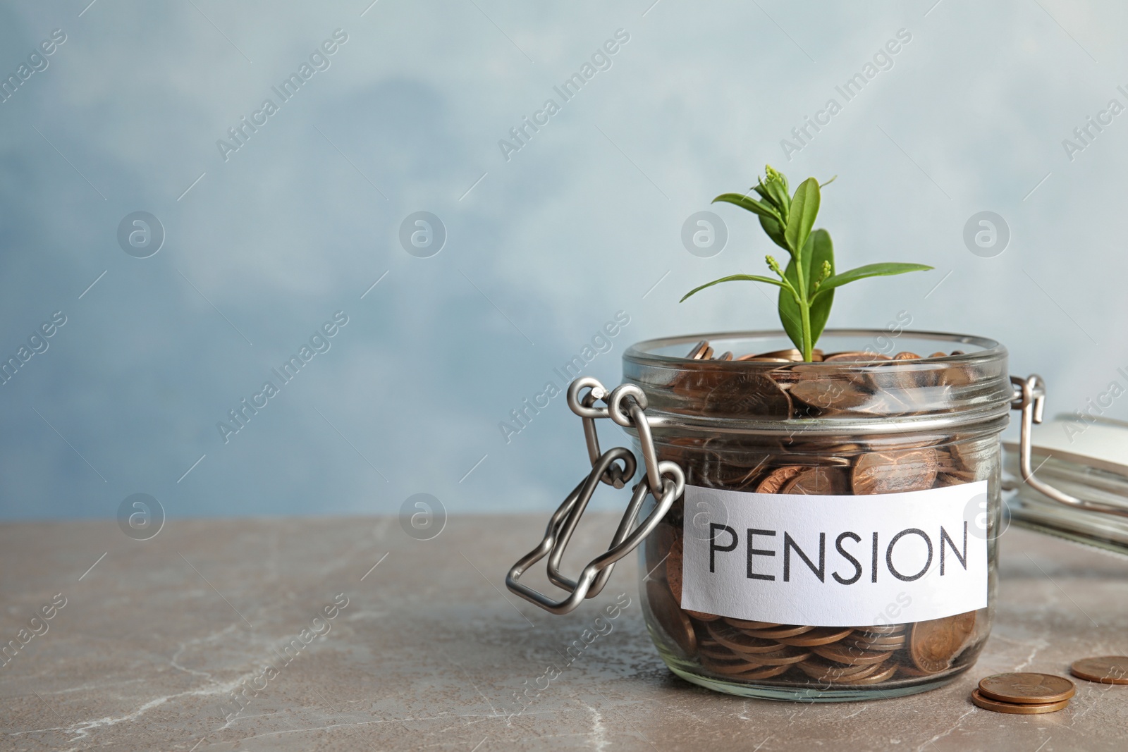 Photo of Glass jar with label PENSION, coins and green plant on marble table. Space for text