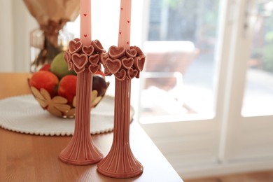 Photo of Bouquet of flowers, bowl with fresh fruits and candles on wooden table indoors, selective focus. Space for text