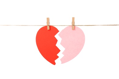 Photo of Halves of paper heart hanging on rope against white background. Relationship problems