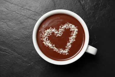 Photo of Cup of hot chocolate with heart shaped decoration on black table, top view