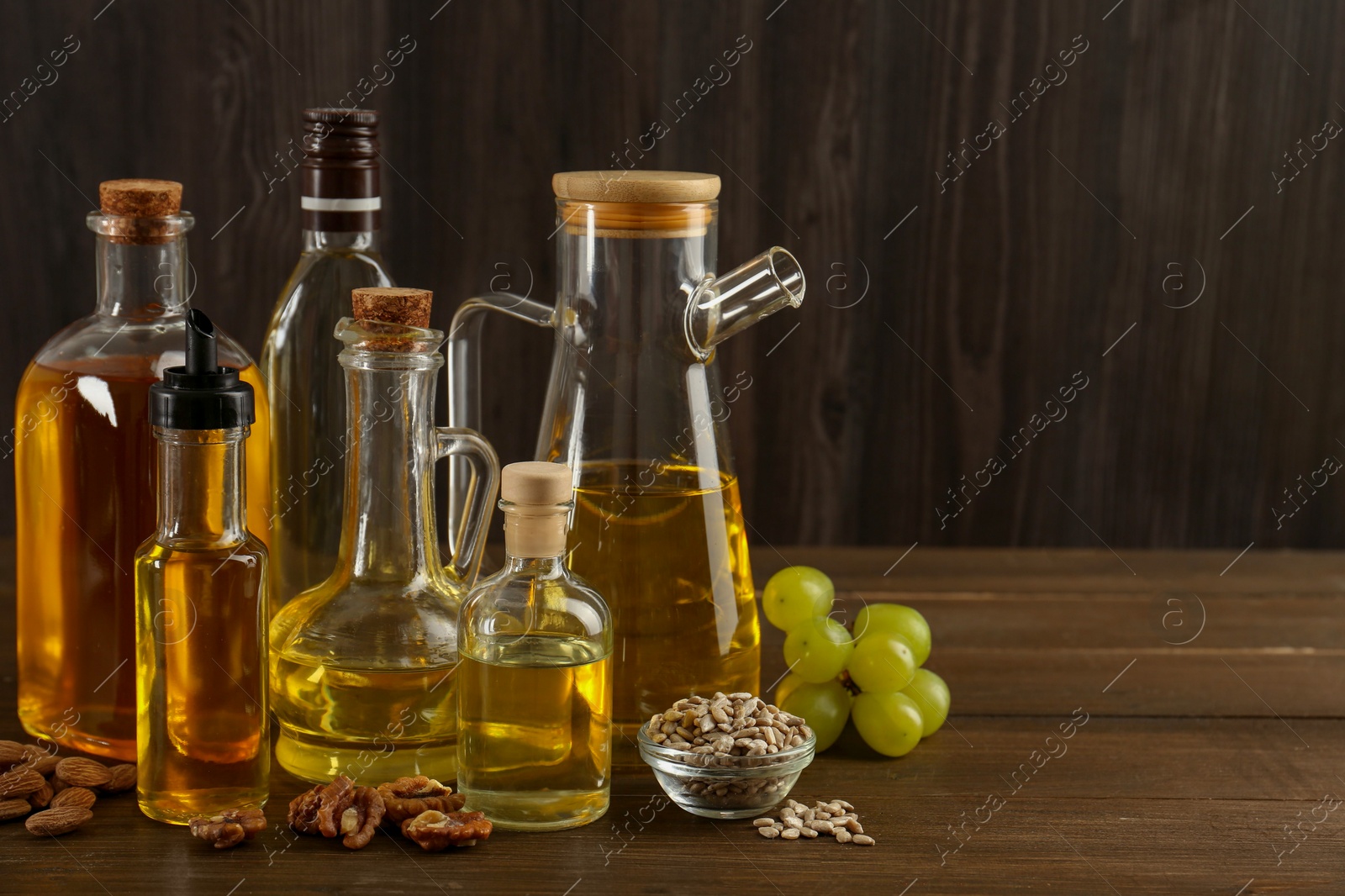 Photo of Vegetable fats. Different oils in glass bottles and ingredients on wooden table, space for text