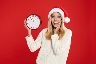 Photo of Woman in Santa hat with clock on red background. New Year countdown