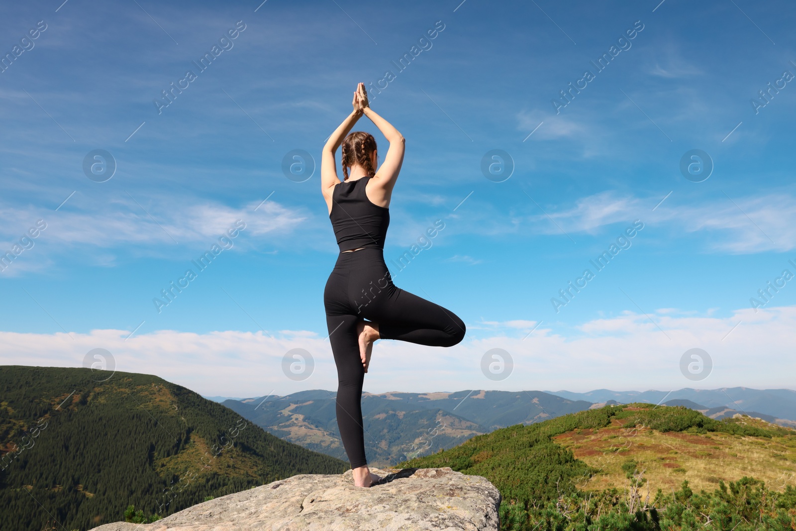 Photo of Young woman practicing outdoor yoga in mountains, back view. Fitness lifestyle