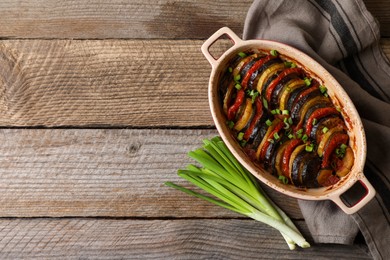 Photo of Delicious ratatouille and green onions on wooden table, flat lay. Space for text