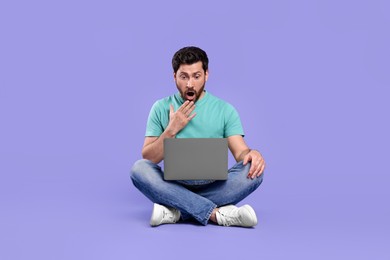 Photo of Emotional man with laptop on purple background