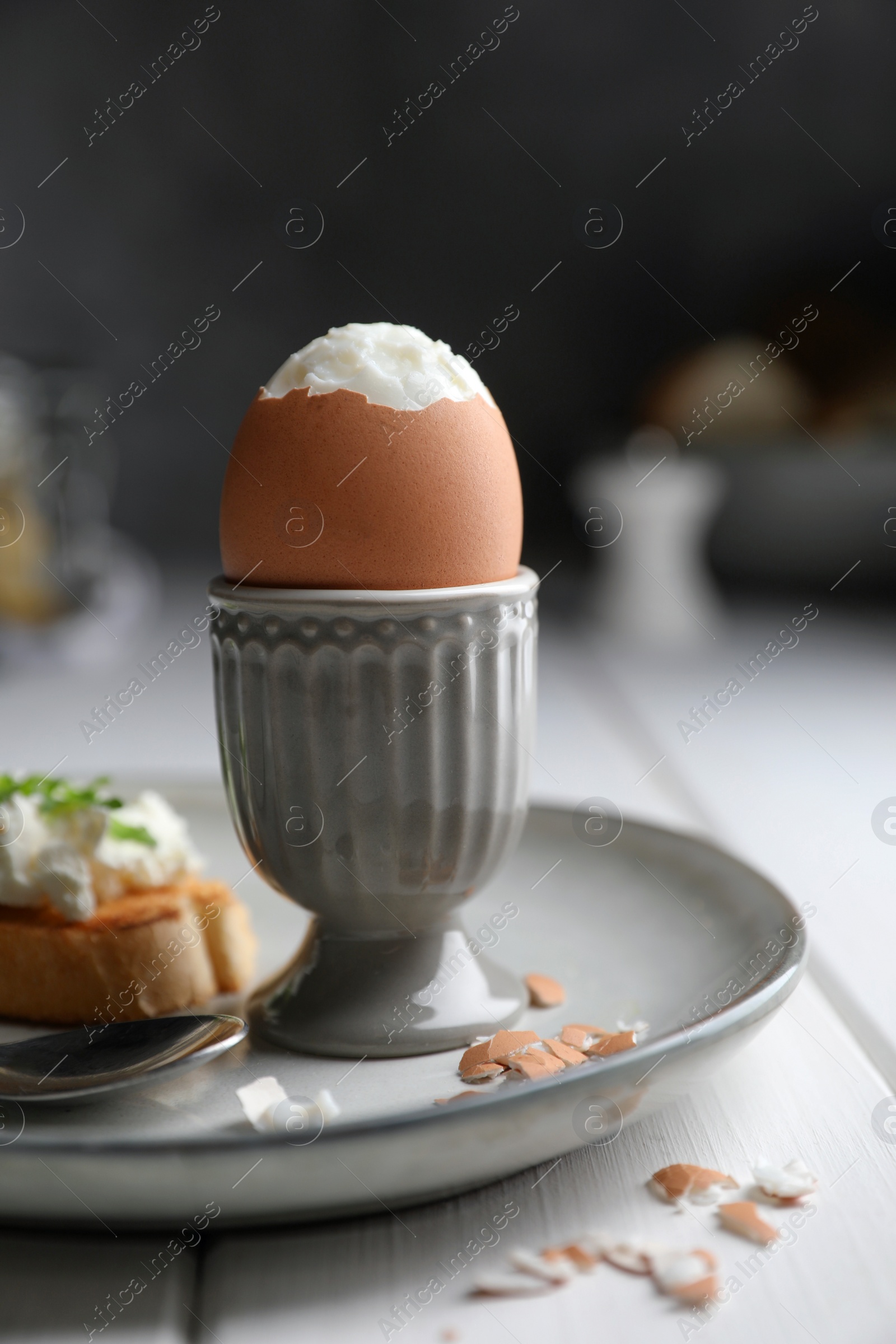 Photo of Fresh soft boiled egg in cup and sandwich on white wooden table