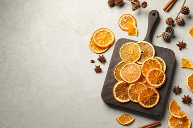 Dry orange slices, cinnamon sticks and anise stars on light grey table, flat lay. Space for text