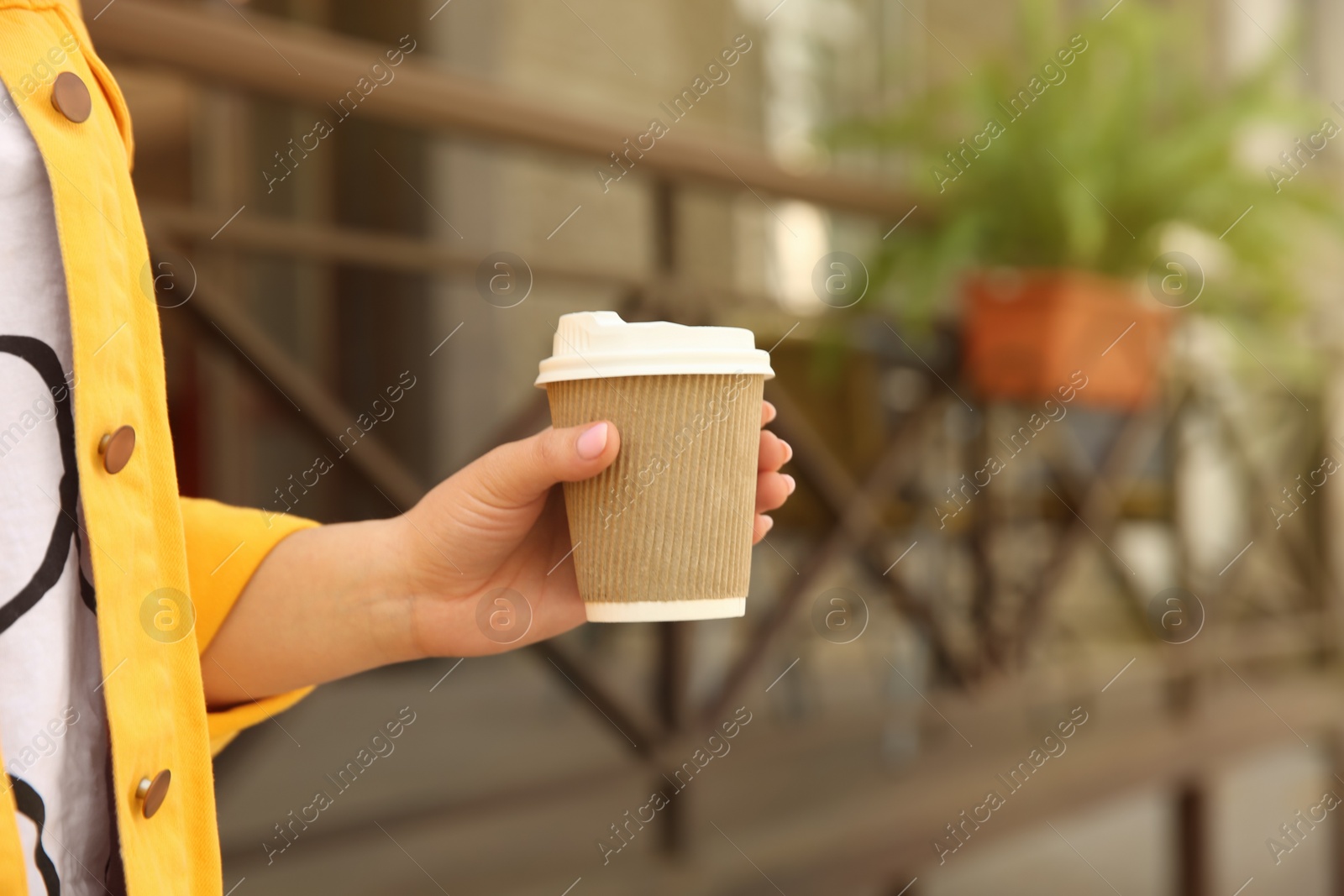 Photo of Woman with takeaway coffee cup outdoors, closeup