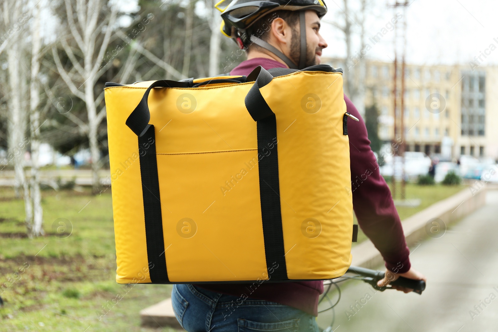 Photo of Courier with thermo bag riding bicycle outdoors. Food delivery service