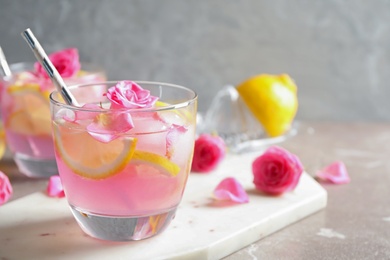 Photo of Delicious refreshing drink with lemon and roses on marble table