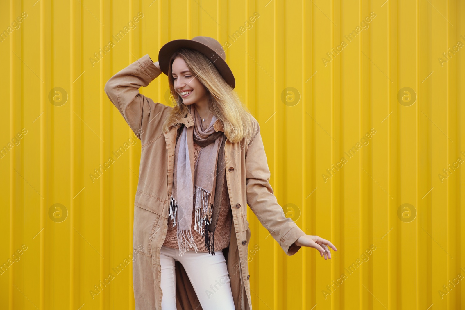 Photo of Beautiful young woman in stylish autumn clothes near yellow fence. Space for text