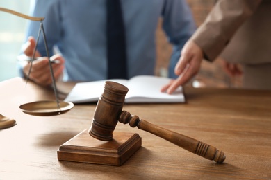 Photo of Notaries working at table in office, focus on judge gavel. Law and justice concept