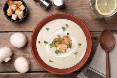 Delicious cream soup with mushrooms served on wooden table, flat lay