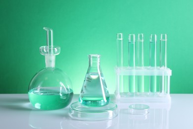 Photo of Laboratory analysis. Different glassware on table against green background