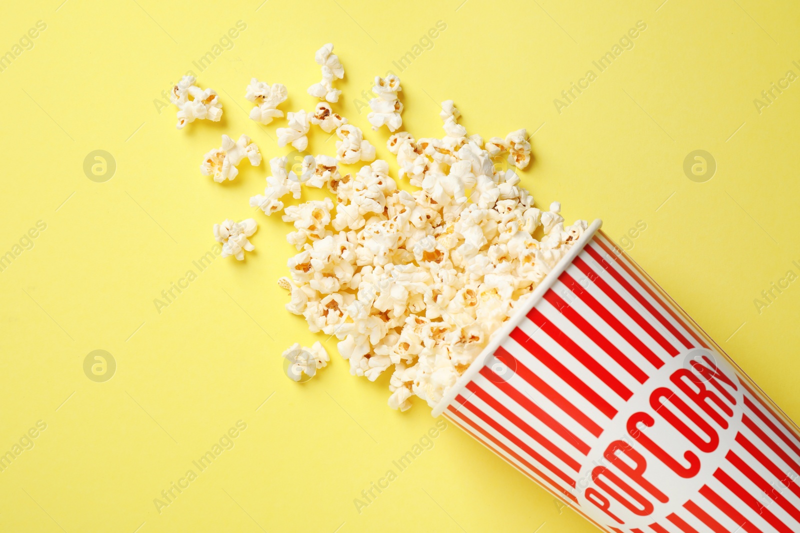 Photo of Delicious popcorn on yellow background, top view