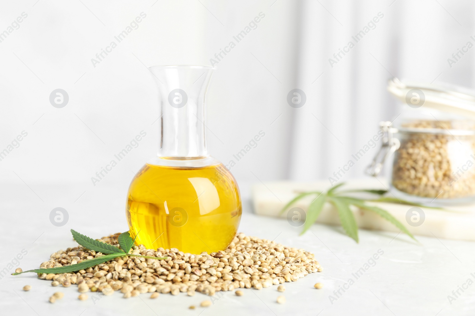 Photo of Bottle with hemp oil, leaf and seeds on white table