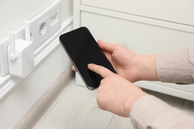 Woman using smartphone for wireless Wi-Fi repeater indoors, closeup