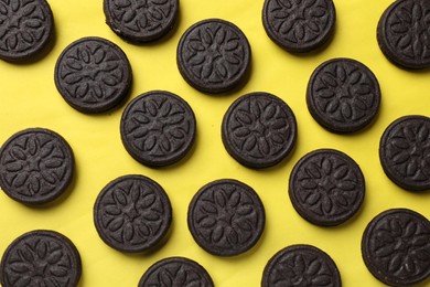 Photo of Tasty sweet sandwich cookies on yellow background, flat lay