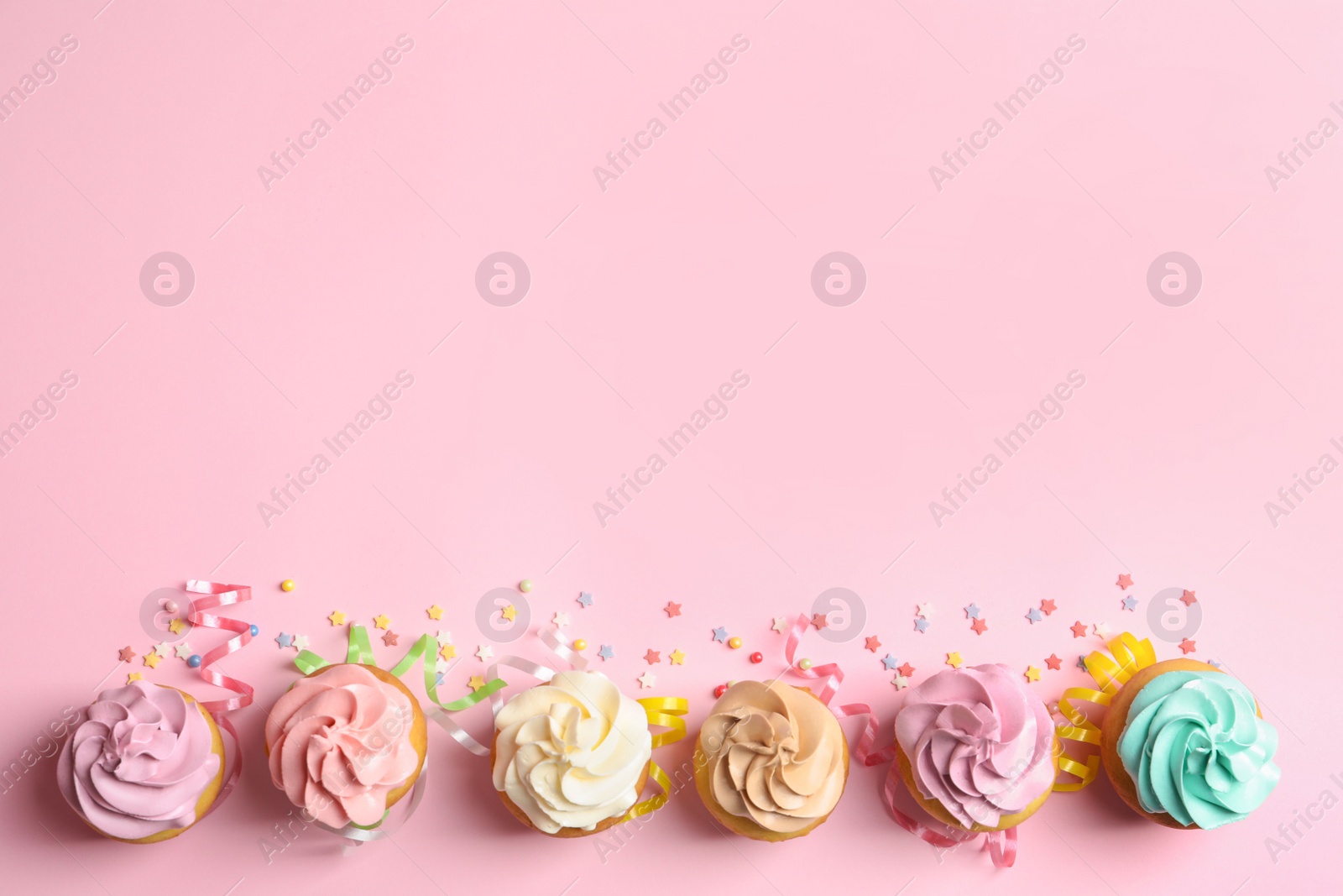 Photo of Flat lay composition with delicious birthday cupcakes and space for text on color background