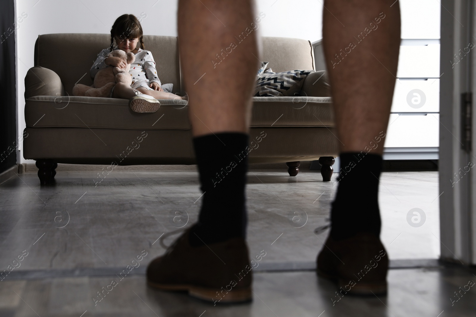 Photo of Adult man without pants standing in front of scared little girl indoors. Child in danger