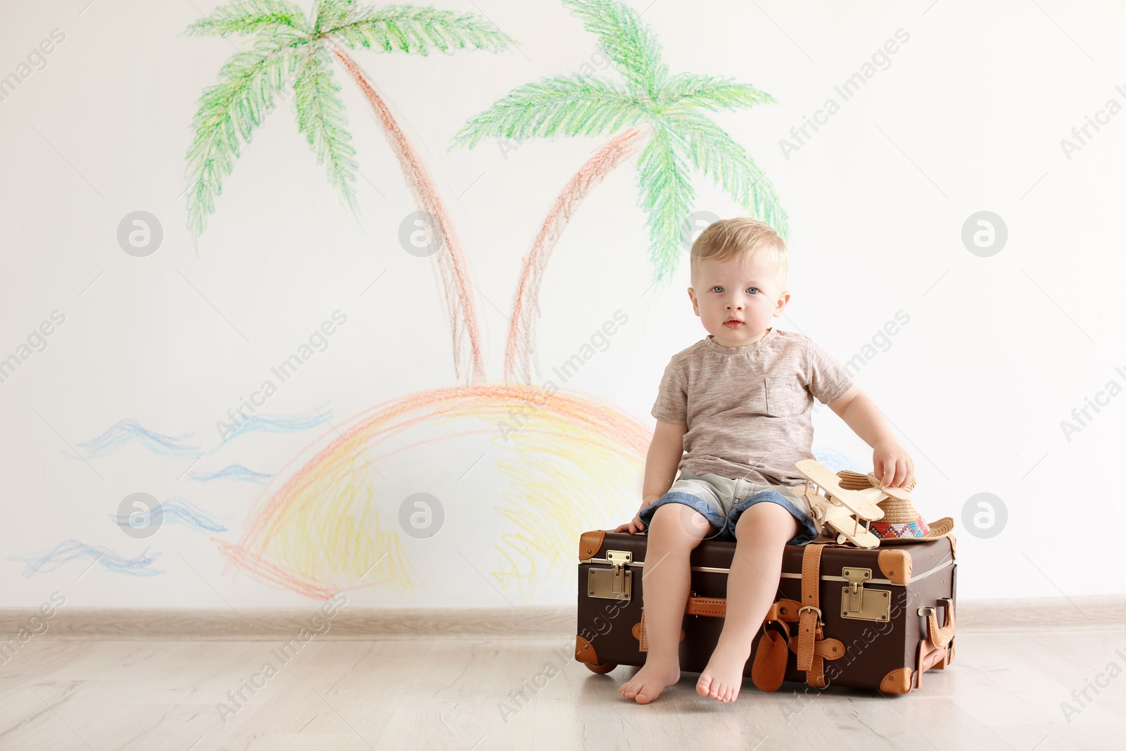 Photo of Adorable little child playing traveler with suitcase indoors