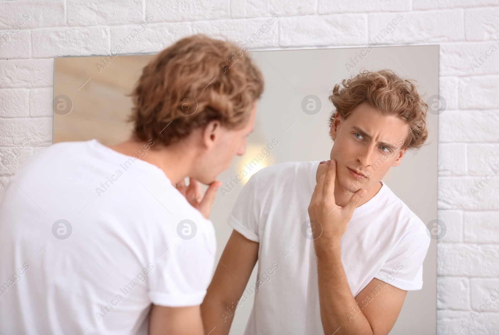 Photo of Young man looking in mirror after shaving at home