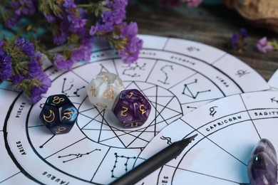 Photo of Zodiac wheels, flowers and astrology dices on wooden table, closeup