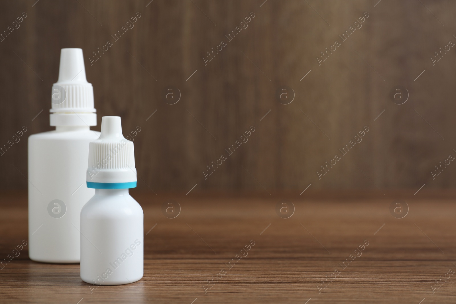 Photo of Bottles of nasal sprays on wooden table. Space for text