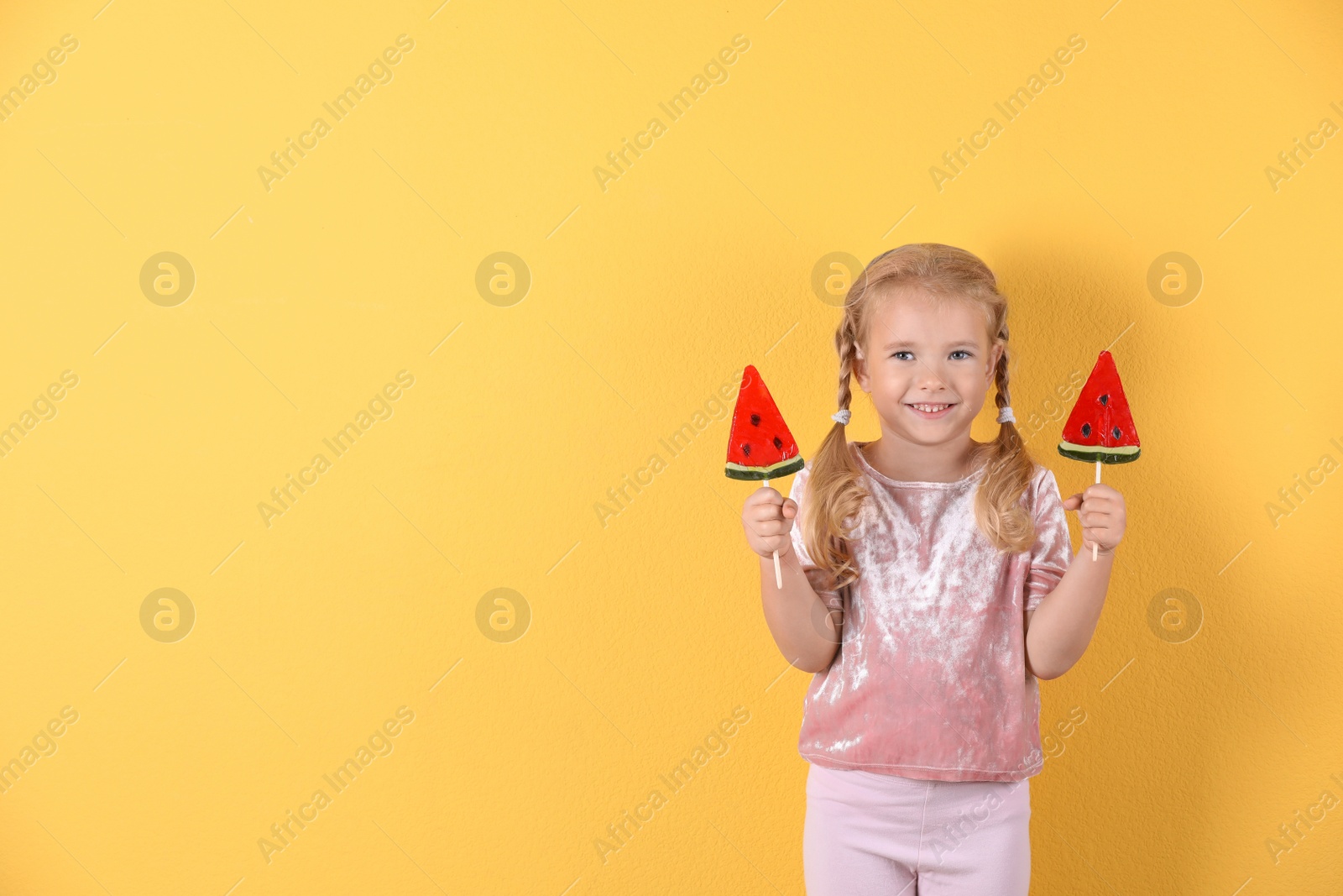 Photo of Cute little girl with candies on color background. Space for text