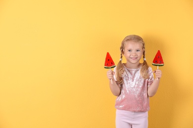 Cute little girl with candies on color background. Space for text