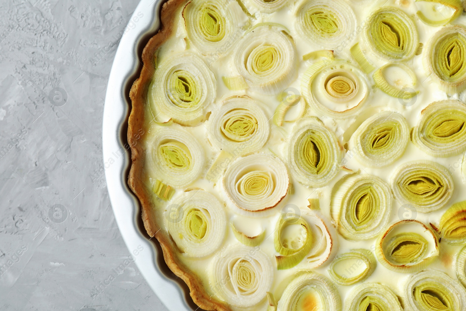 Photo of Freshly baked leek pie on grey textured table, top view