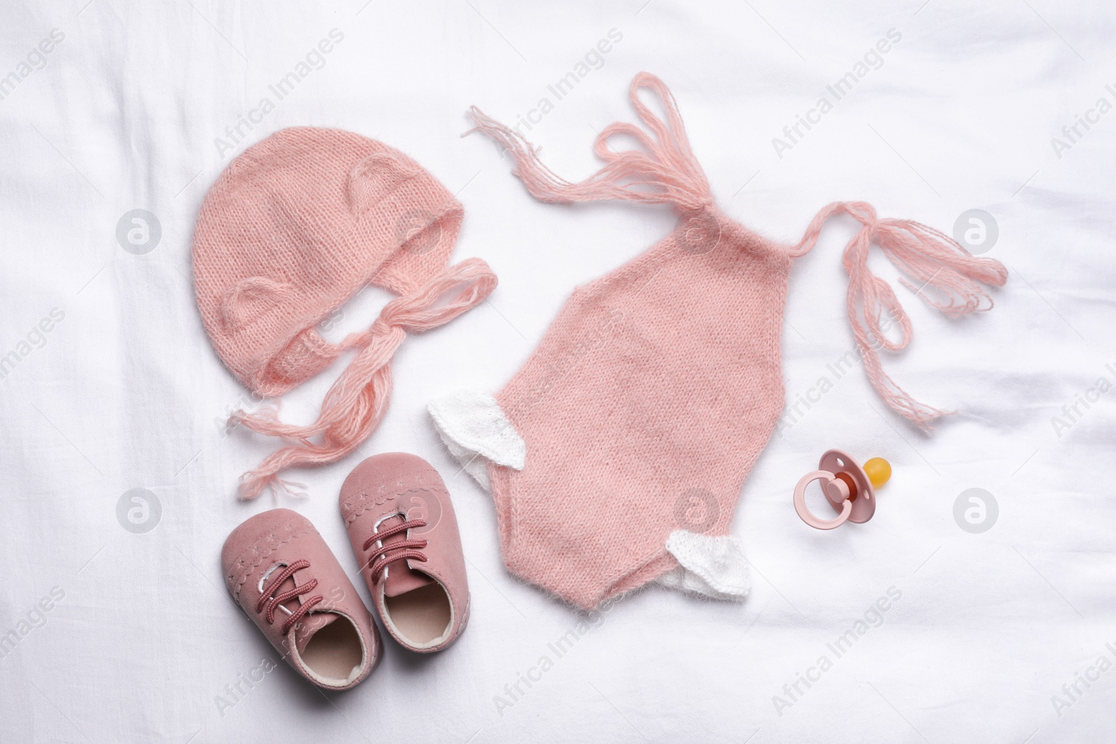 Photo of Flat lay composition with child's clothes and accessories on white fabric