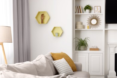 Photo of Spring atmosphere. Soft sofa, lamp and shelves with stylish accessories in room