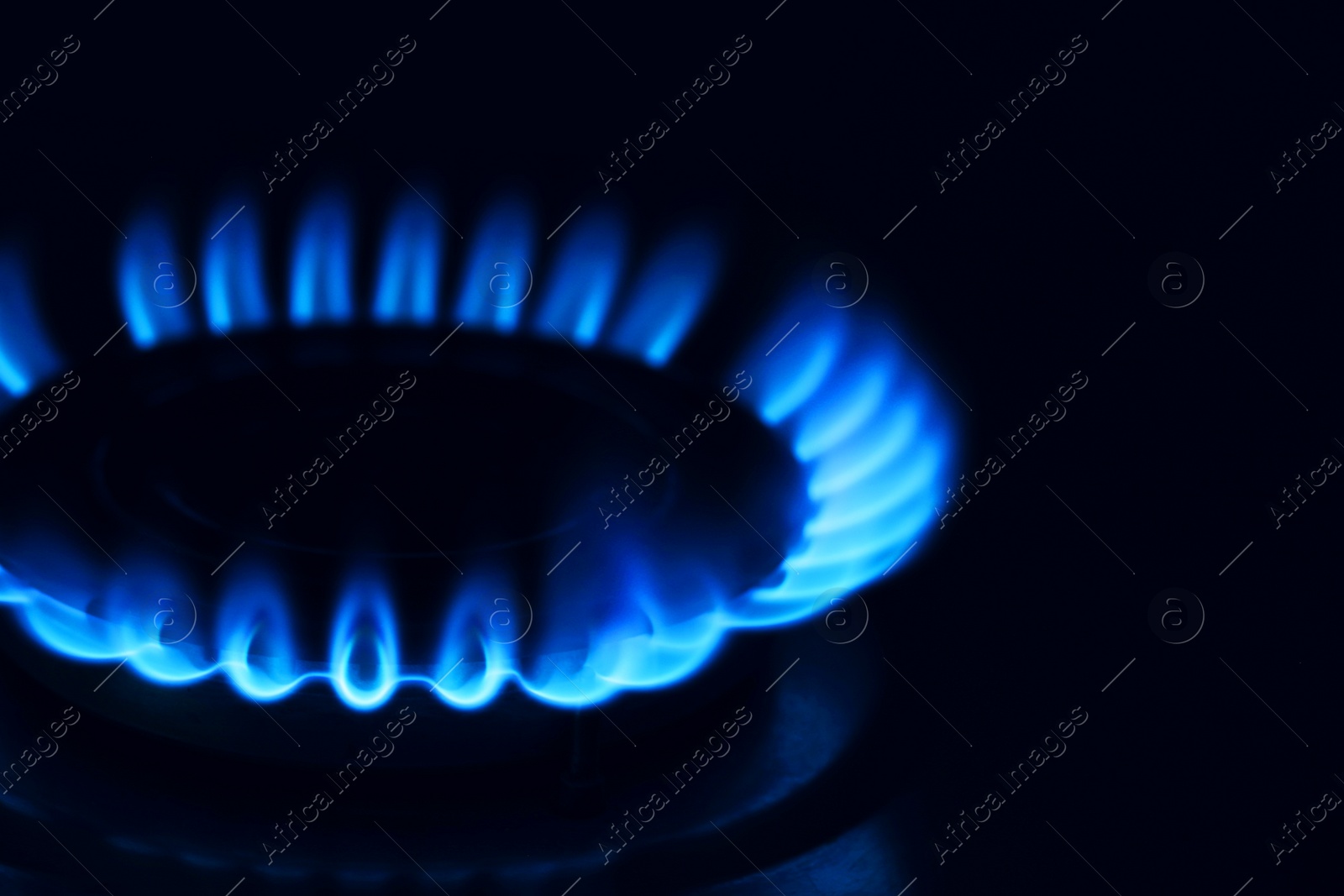 Photo of Gas burner with burning flame in darkness, closeup