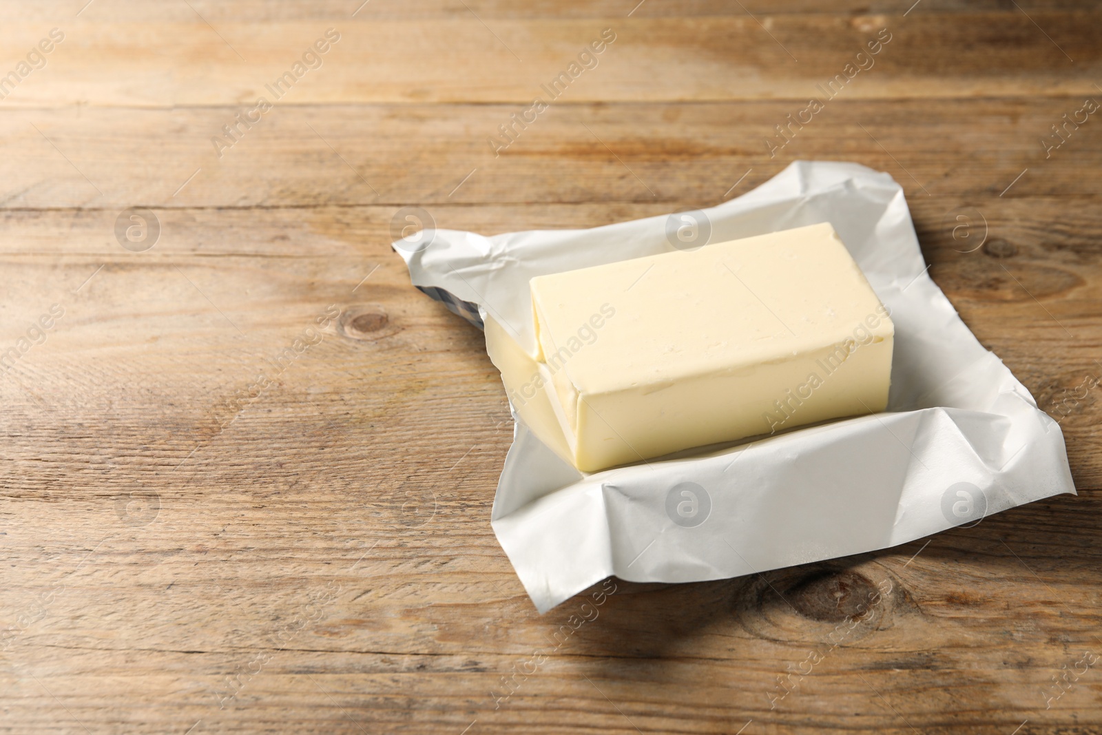 Photo of Block of tasty butter on wooden table. Space for text