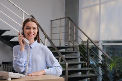Photo of Female receptionist talking on phone at workplace. Space for text