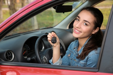 Happy woman showing key from new car