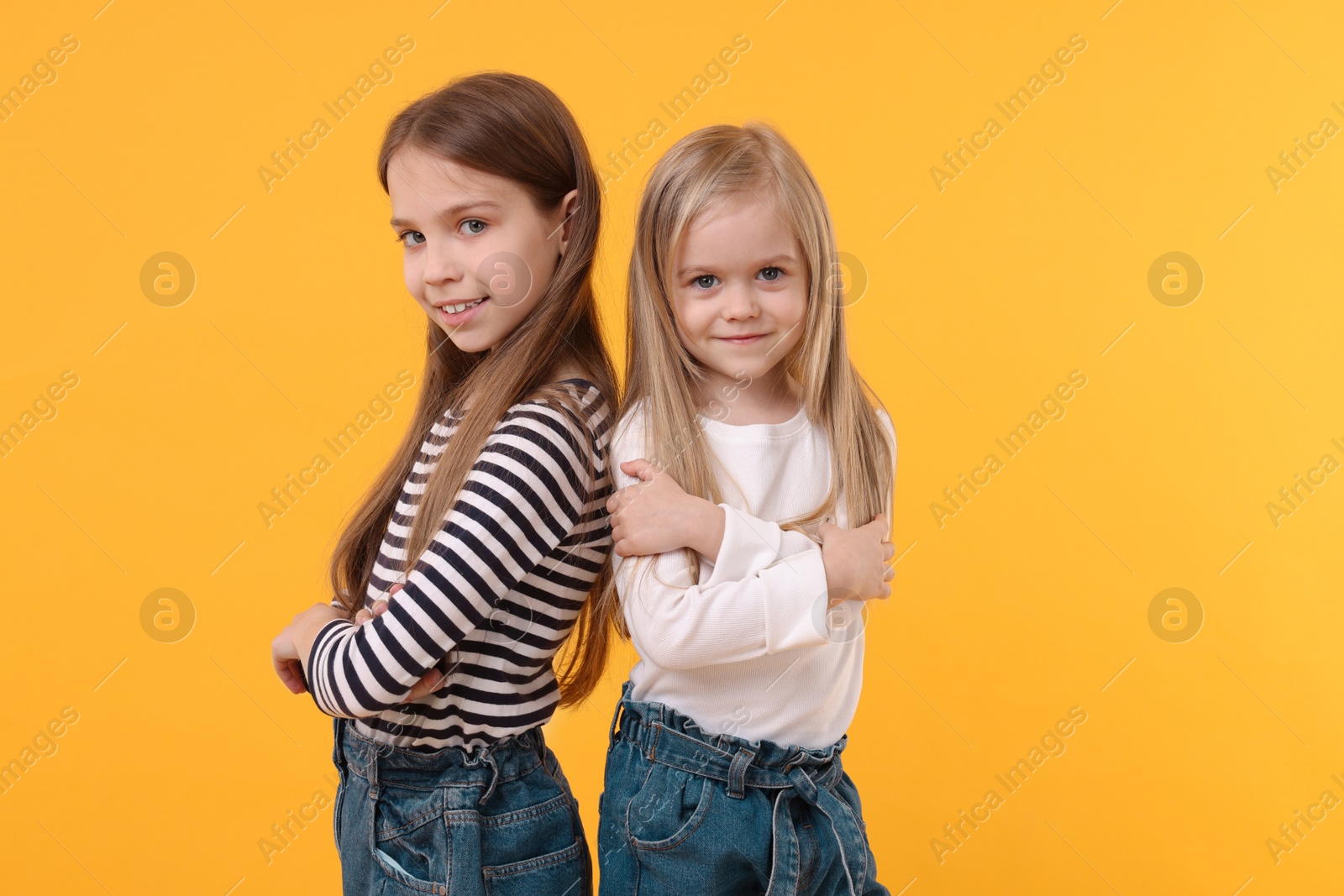 Photo of Portrait of cute little sisters on orange background