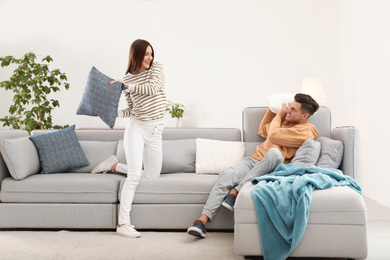 Photo of Happy couple having pillow fight in living room