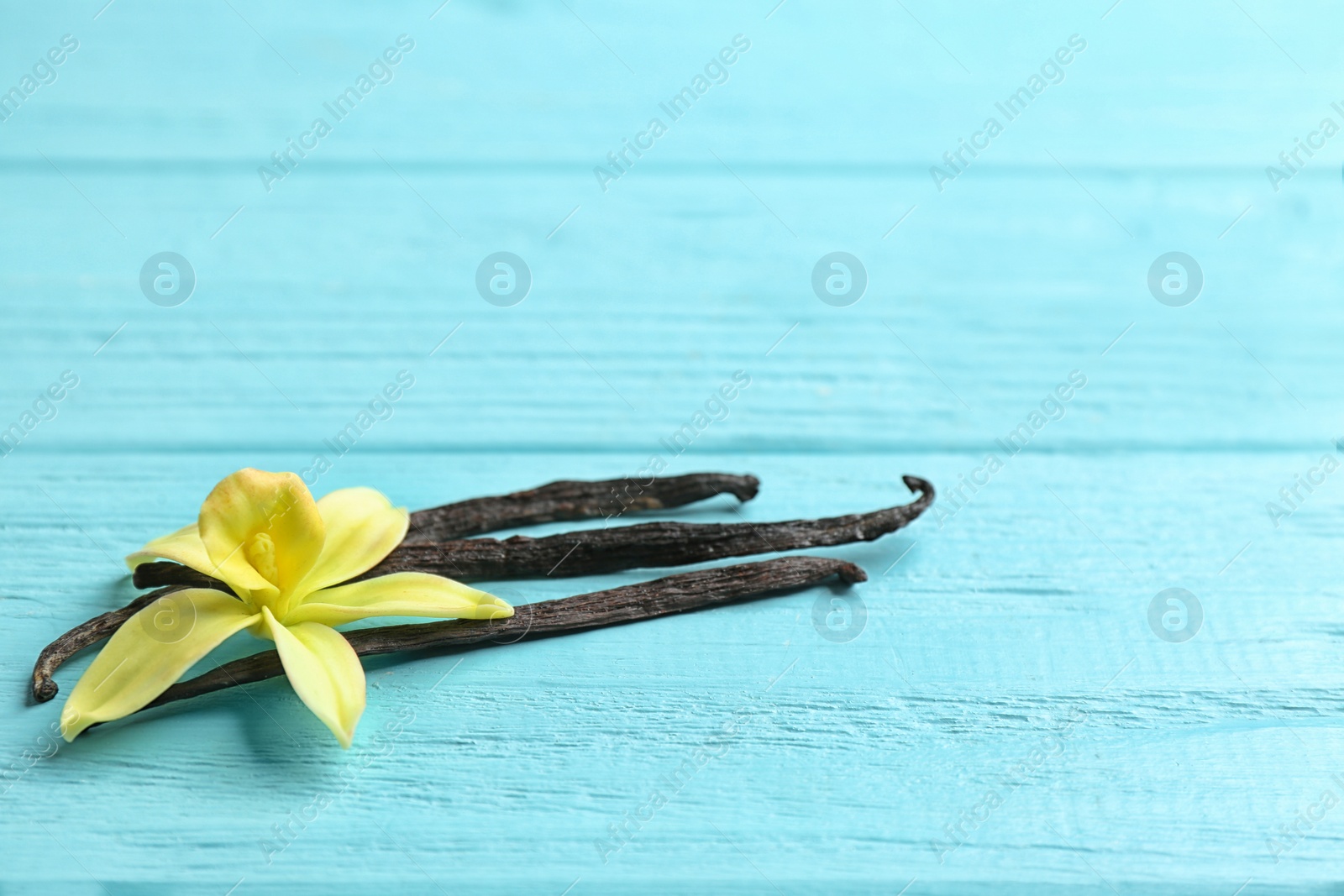 Photo of Vanilla sticks and flower on wooden background. Space for text