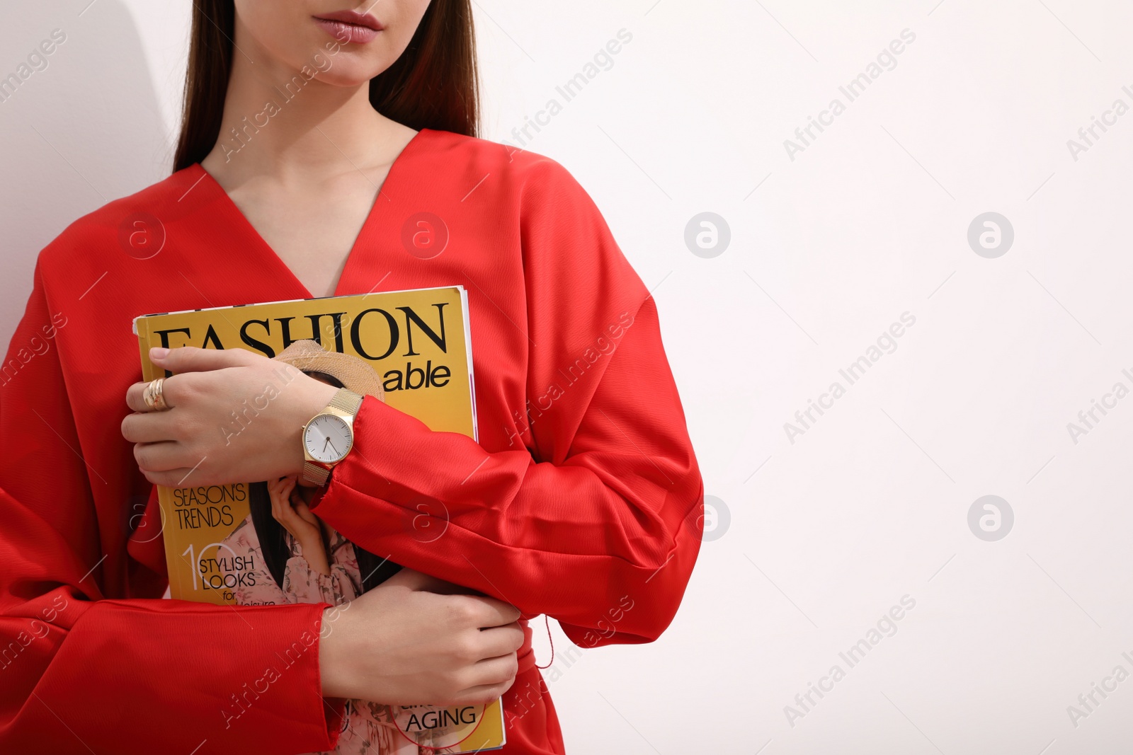 Photo of Woman with fashion magazine near white wall, closeup. Space for text