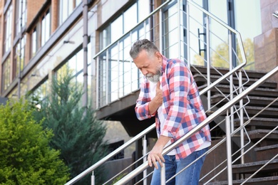 Mature man having heart attack on stairs, outdoors